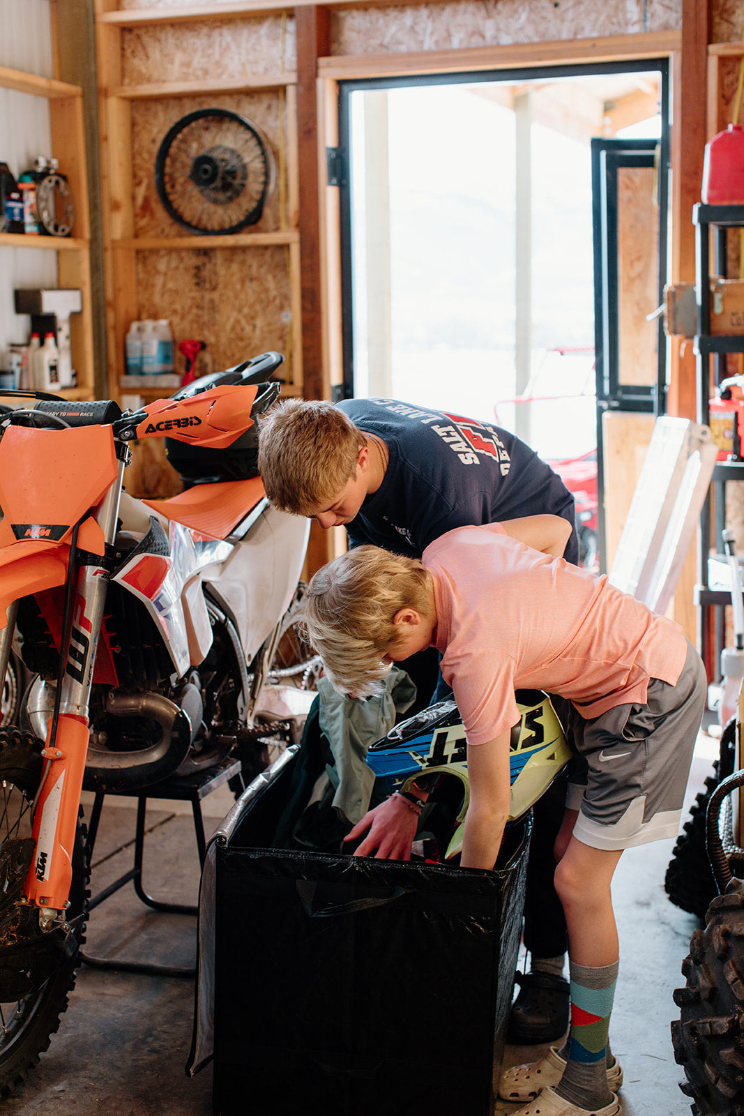 Two teenagers packing dirt biking gear into an open Burro Bag